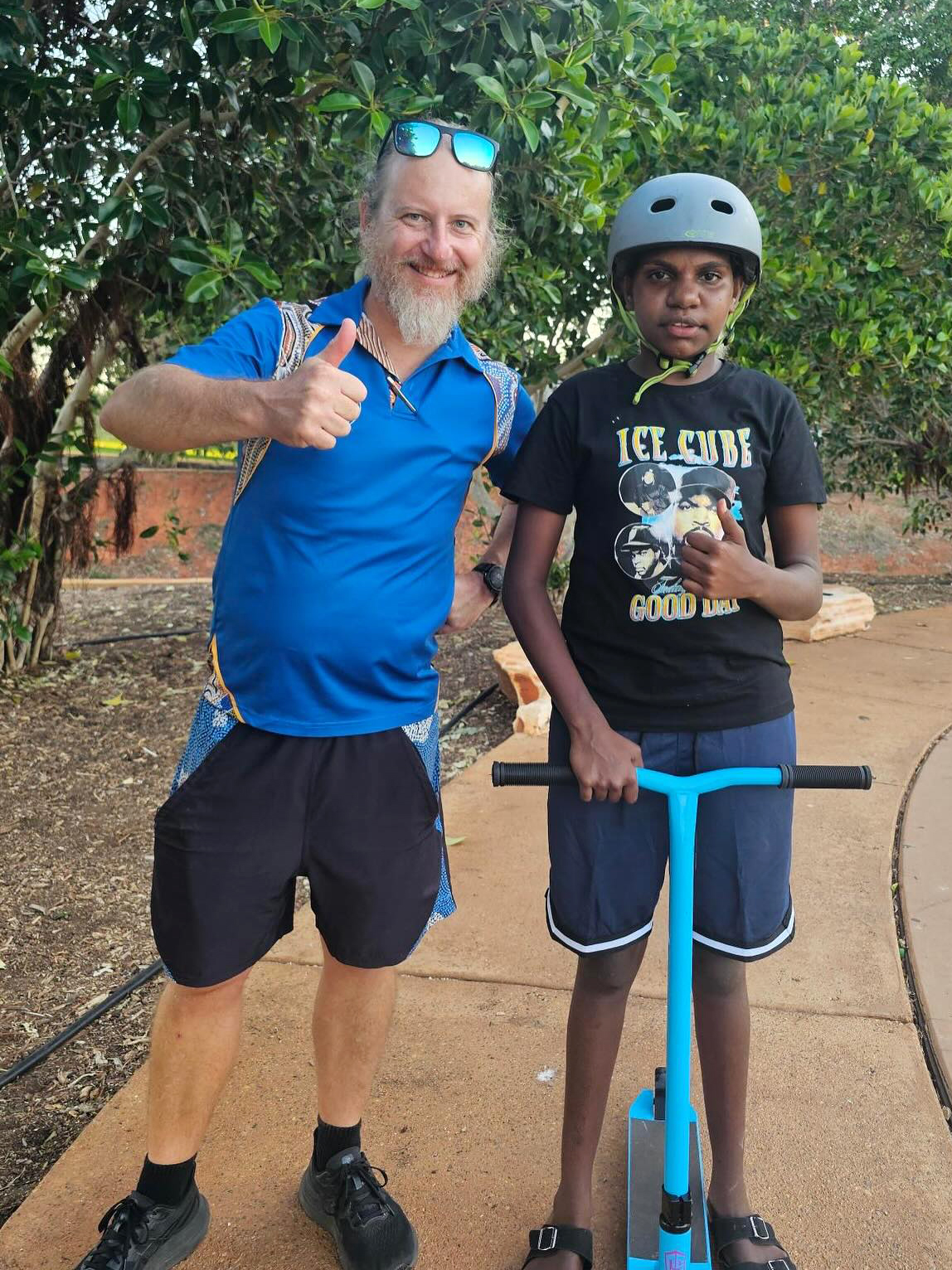 Boarding Supervisor from Broome Residential College with a boarder who is standing on a scooter.