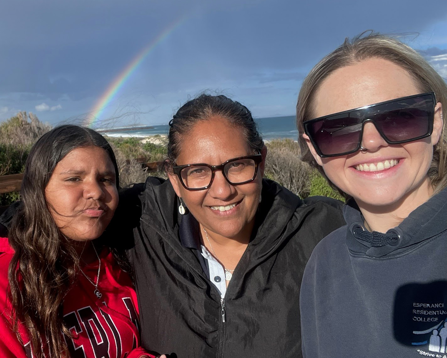 Esperance Residential College supervisors smiling in front of an afternoon rainbow.