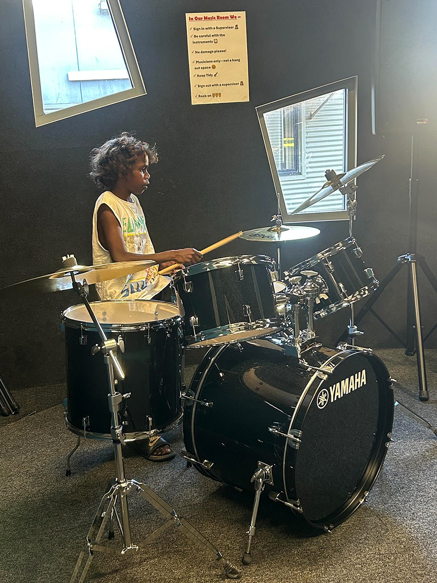 Broome Residential College boarder playing on the college drumkit.