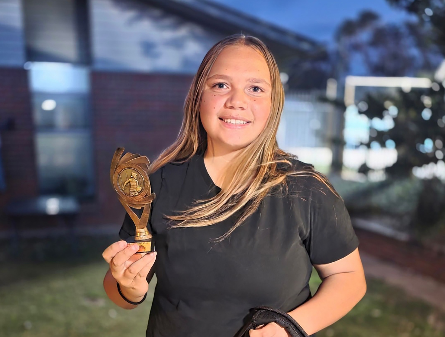 Geraldton Residential College boarder proudly showing her winner's trophy for football.
