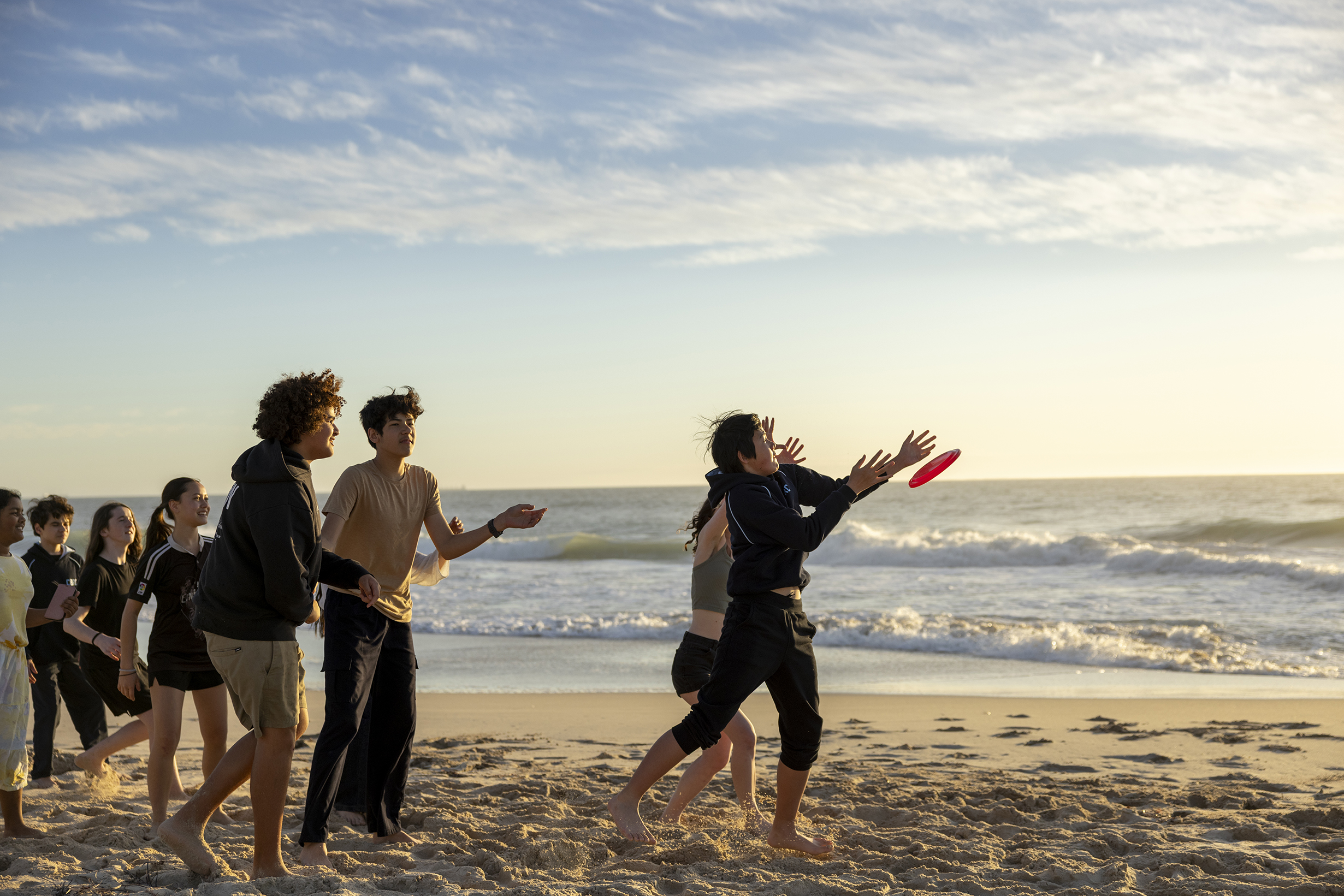 City Beach Residential College boarders playing frisbee on the beach.