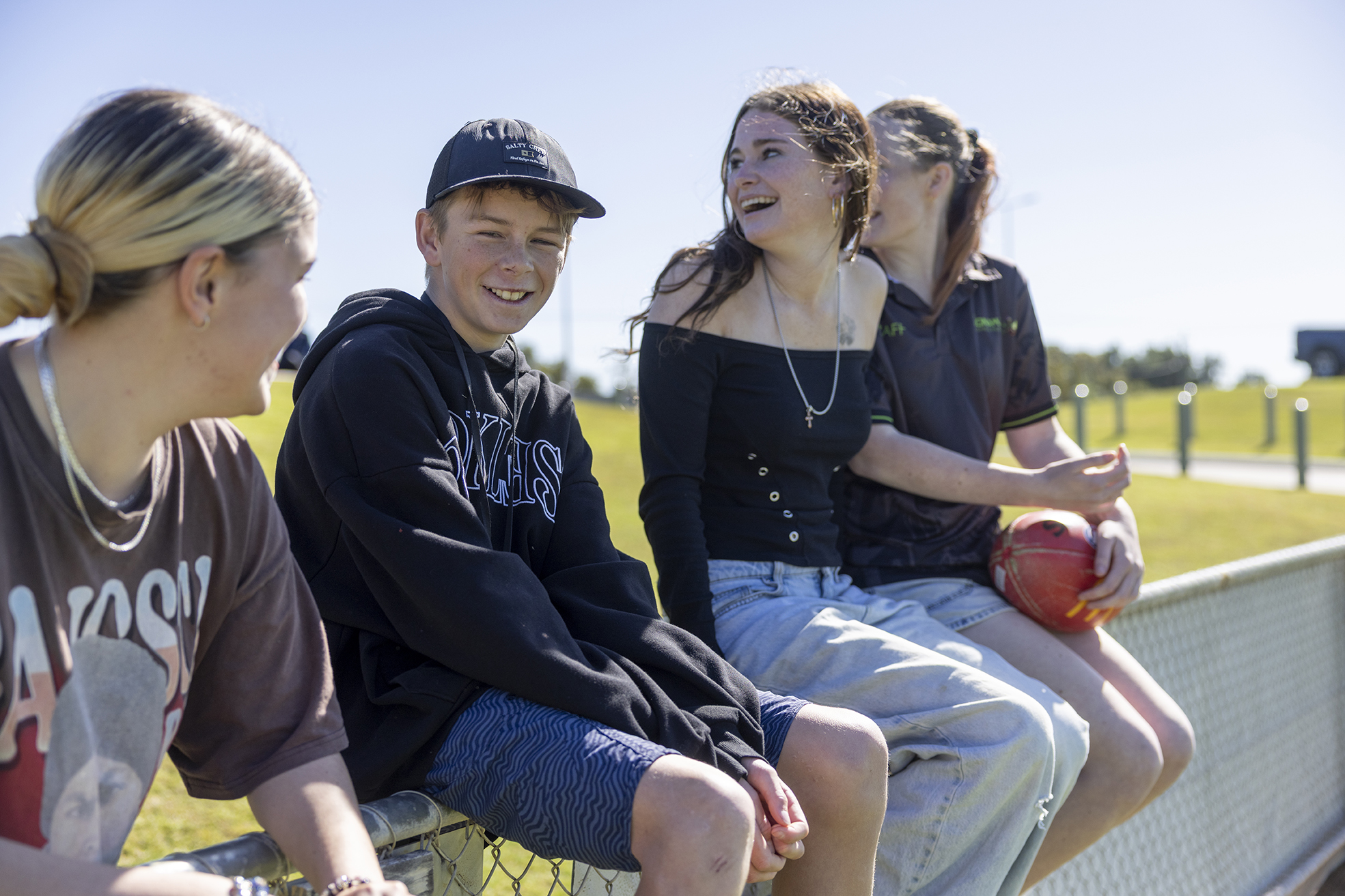 Boarders from Geraldton Residential College sitting a fence watching a local footy game.