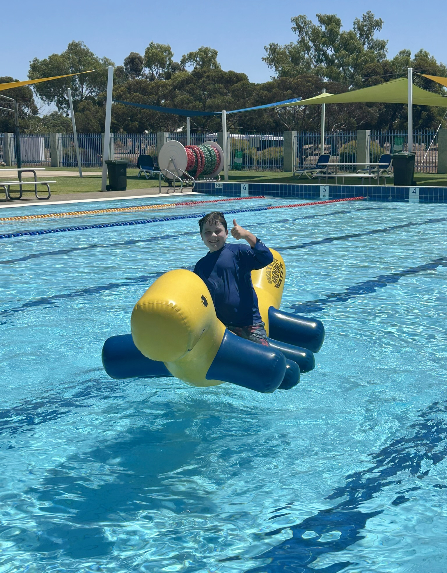 Merredin Residential College boarder sitting on an inflatable at the local community pool.