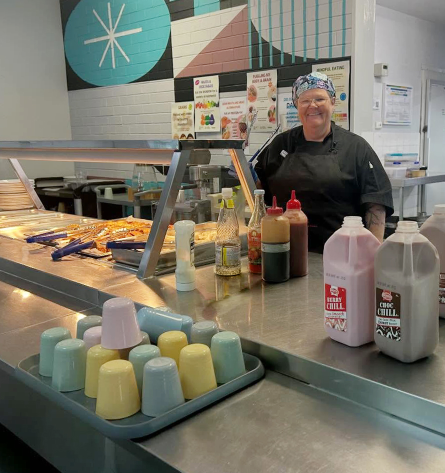 Smiling chef at Albany Residential College serving afternoon tea of muffins and flavoured milk