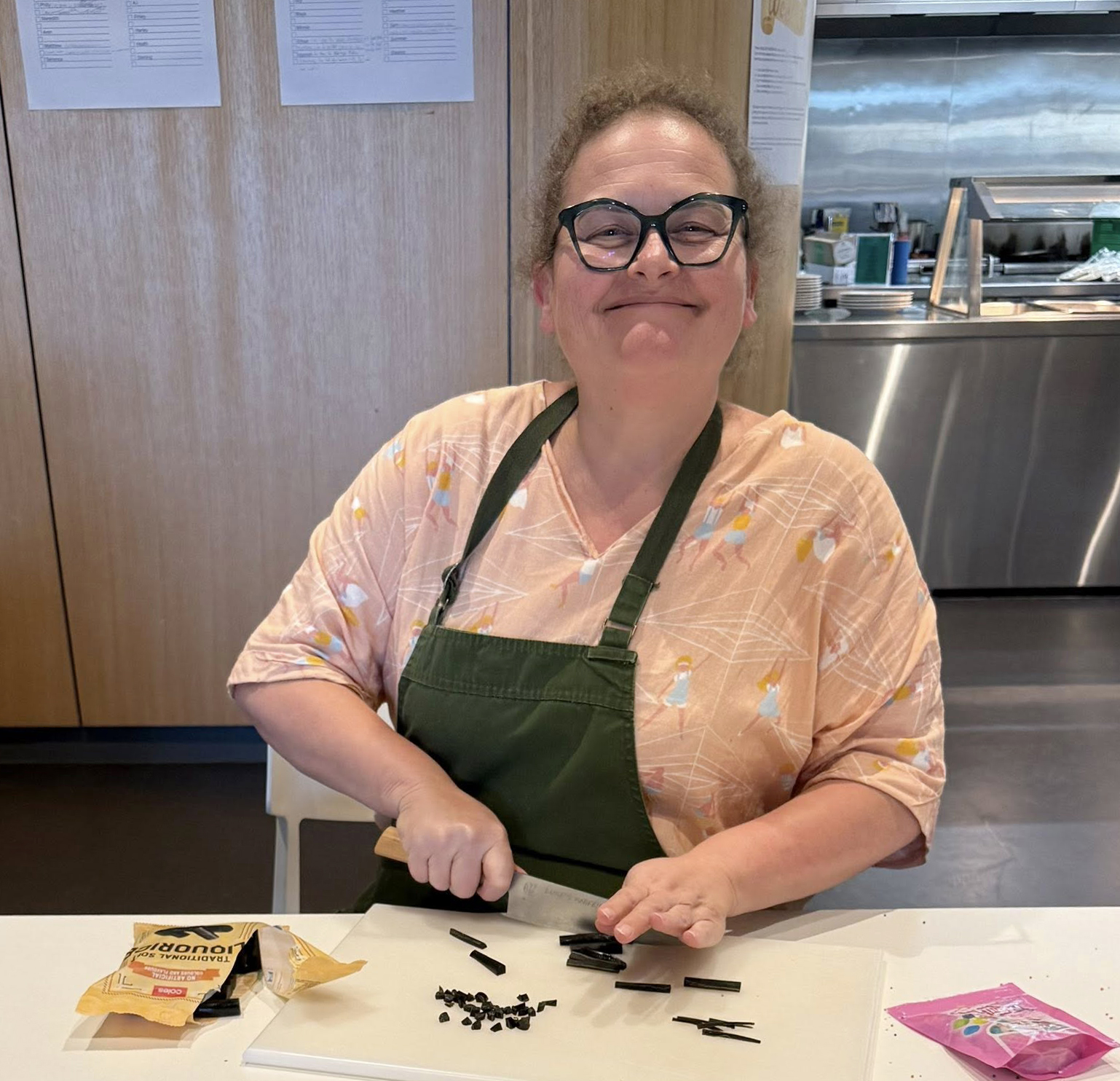 A smiling boarding supervisor cutting licorice for a cookie-decorating activity