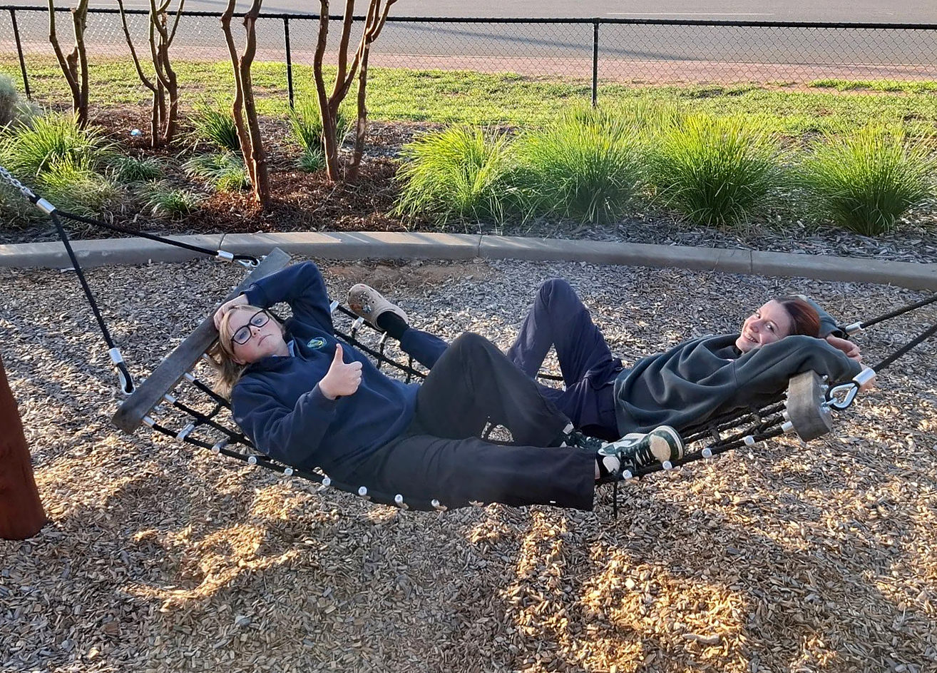 2 Merredin Residential College boarders swinging on a hammock at the local park.