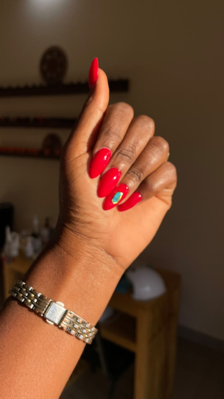 Manucure rouge vif avec accent bijou d'ongle