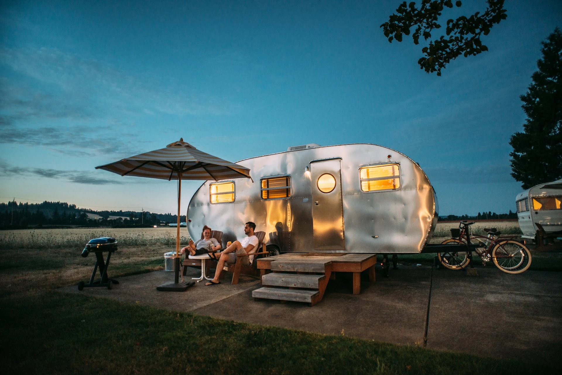Pareja en el exterior de una caravana instalada en un camping