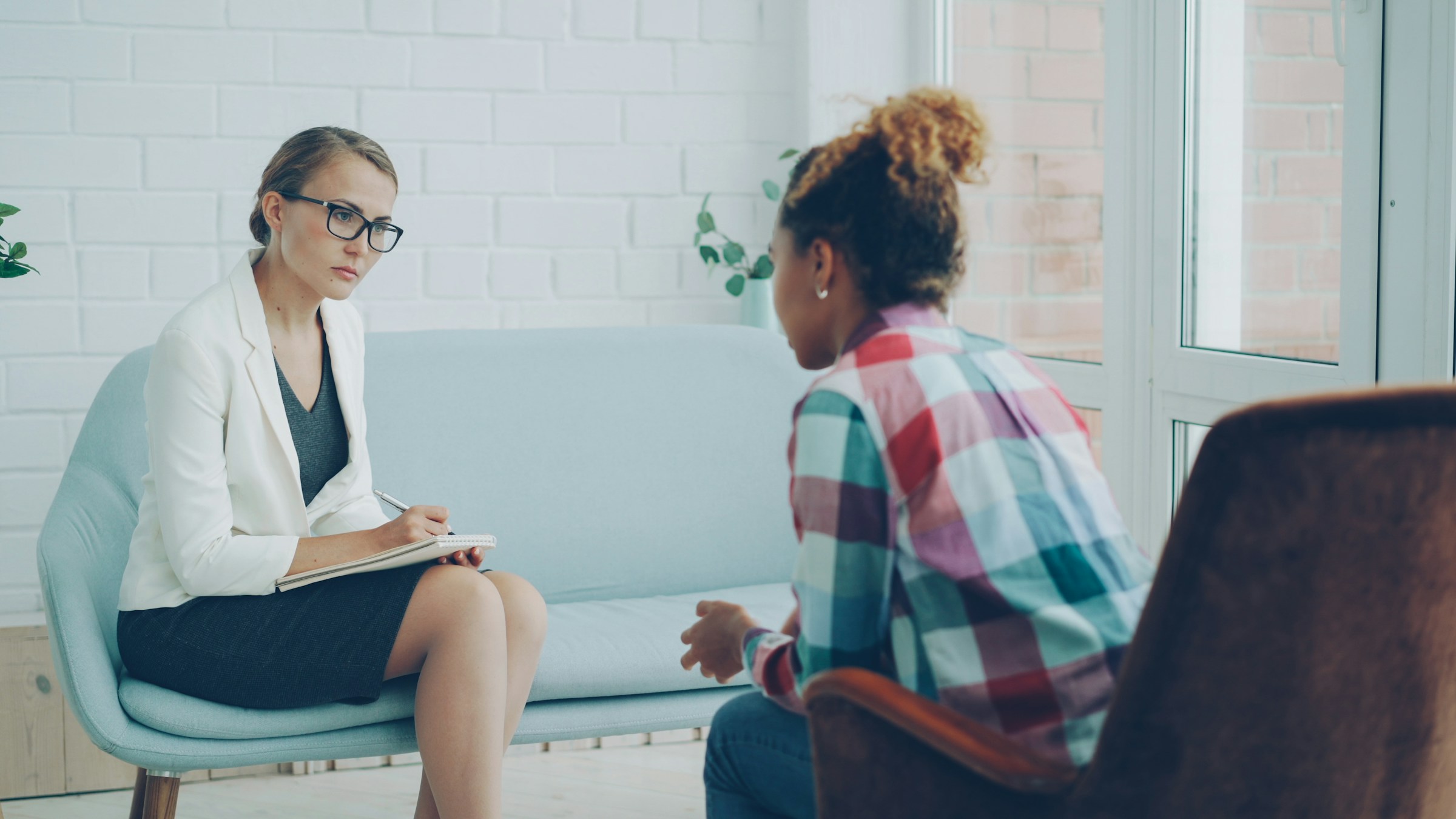 A therapist actively listening and taking notes while a client shares during a counselling session A therapist actively listening and taking notes while a client shares during a counselling session