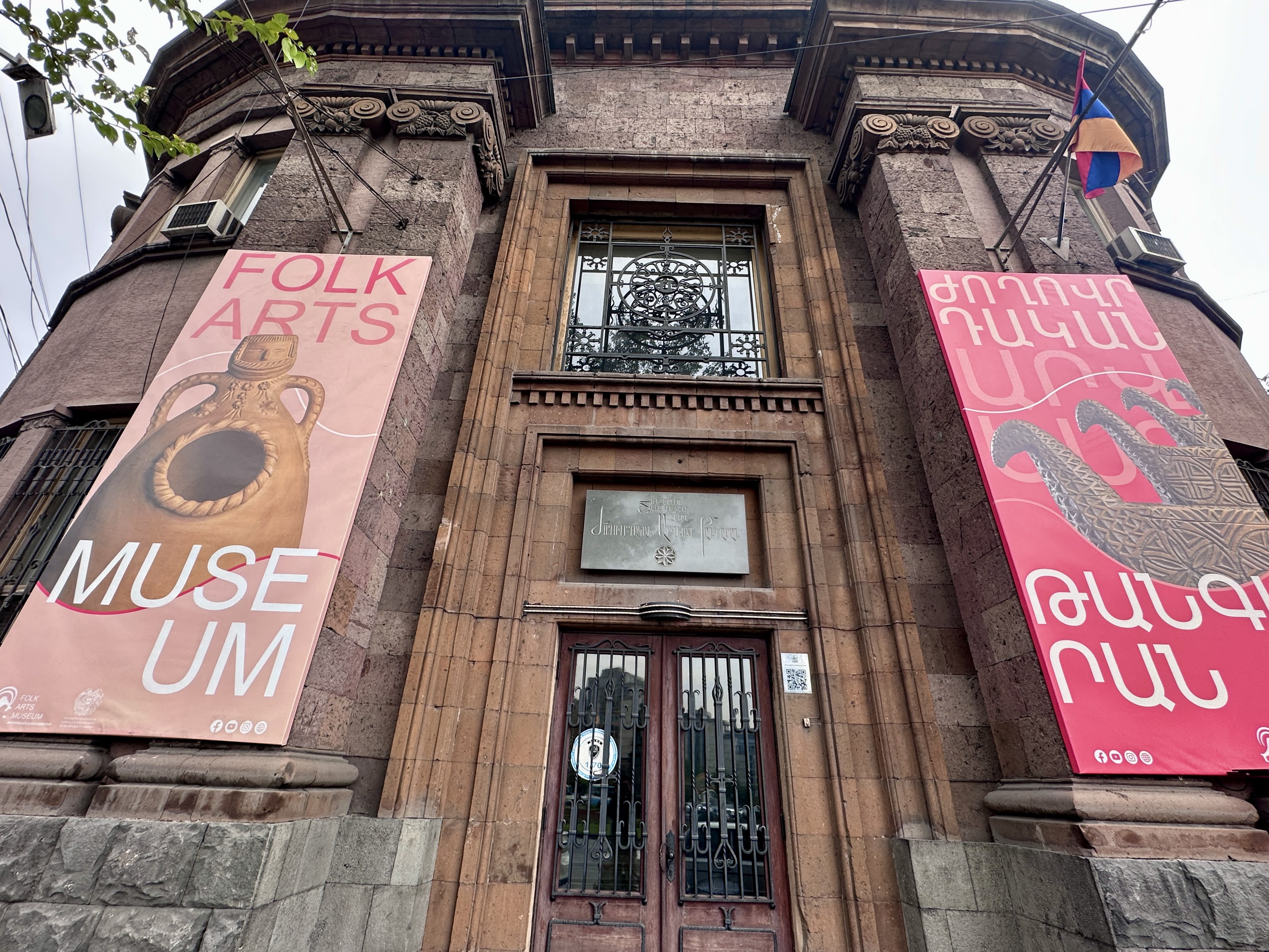 A building in Yerevan adorned with vibrant banners on the side showcases the city's rich culture and invites you to explore the diverse activities within.