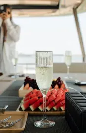 An image of a glass of champaign and a watermelon dish 