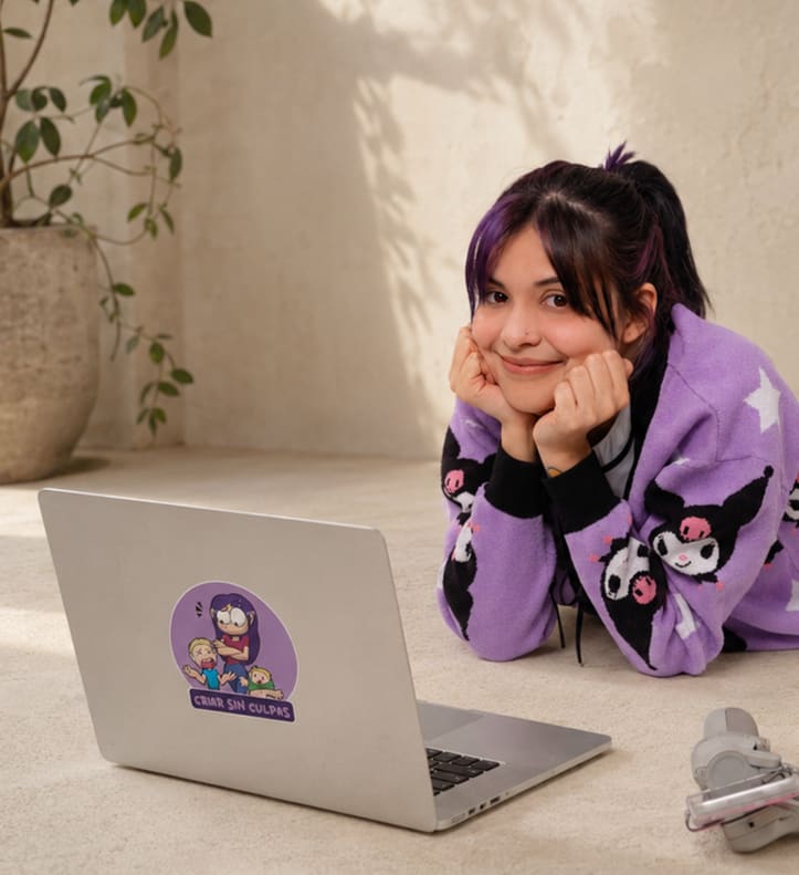 Nari sonríe junto a su laptop con el sticker de Criar Sin Culpas