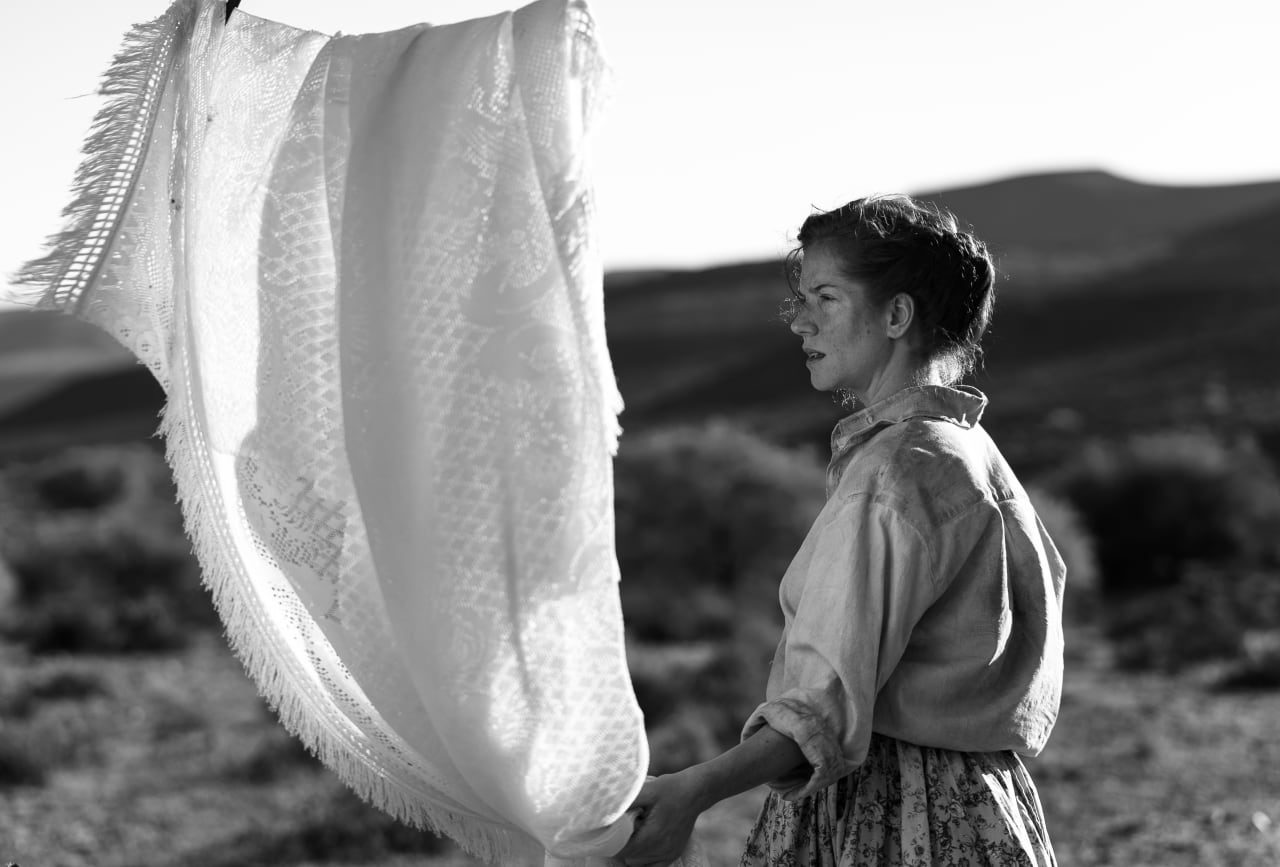 Editorial visual representing Nico Scheepers’ Hen, featuring a stark black-and-white Limpopo farm landscape, psychological horror atmosphere, a wooden chest, rural silence, religious dread, festival-award glow, deep shadows, silver highlights and premium Viranova glass styling.