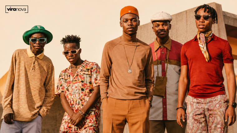 Editorial visual representing The Joy’s “Precious” as South African vocal harmony entering global pop space, with five vocalist silhouettes, warm stage lighting, studio textures, festival-scale atmosphere and premium Viranova purple-and-gold glass styling.
