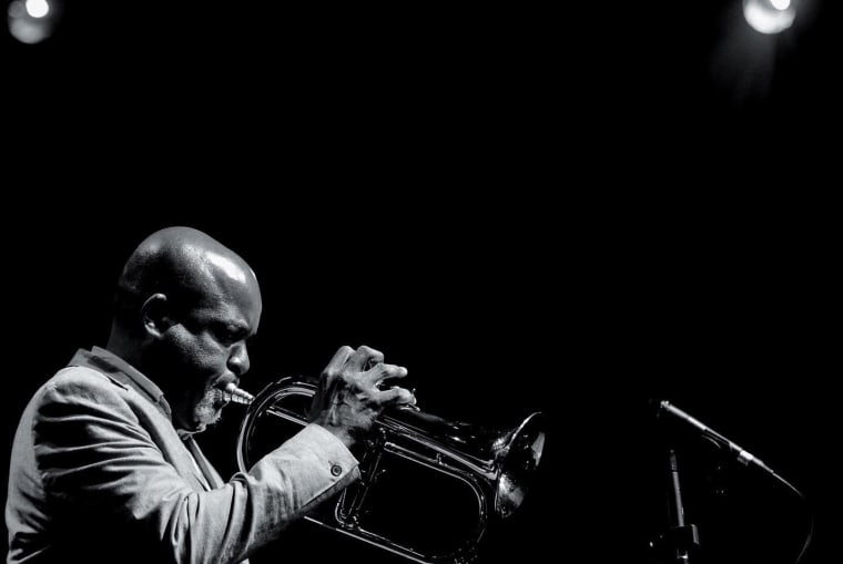 Editorial visual representing Sydney Mavundla’s Jazz at Jozi Gold performance in Braamfontein, featuring warm trumpet-stage light, brewery atmosphere, 81 De Korte Street cultural memory, Orbit-inspired jazz textures and premium Viranova purple-and-gold glass styling.