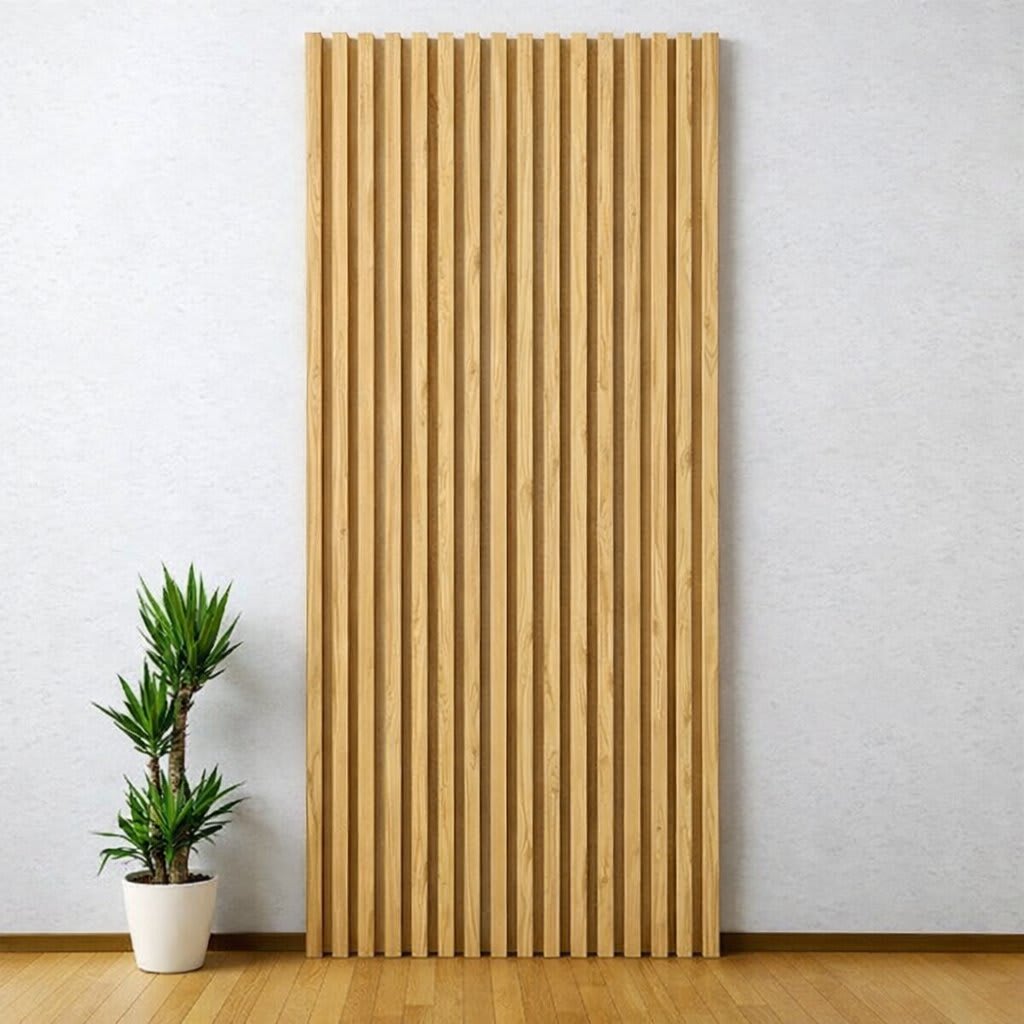 A tall, vertical WPC wall panel with blonde textured slats stands out against a light-colored wall in a minimalist, modern interior, paired with a small potted plant on a warm wooden floor, creating a serene and clean design.