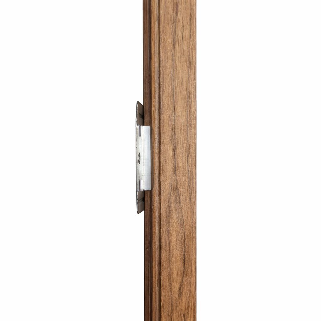 Close-up view of a wooden door jamb showing a metal strike plate and latch hardware mounted on a brown wood frame, highlighting texture, grain and construction detail for home improvement and carpentry.