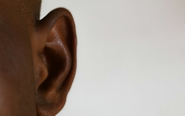 Close-up of an adult ear against a plain background