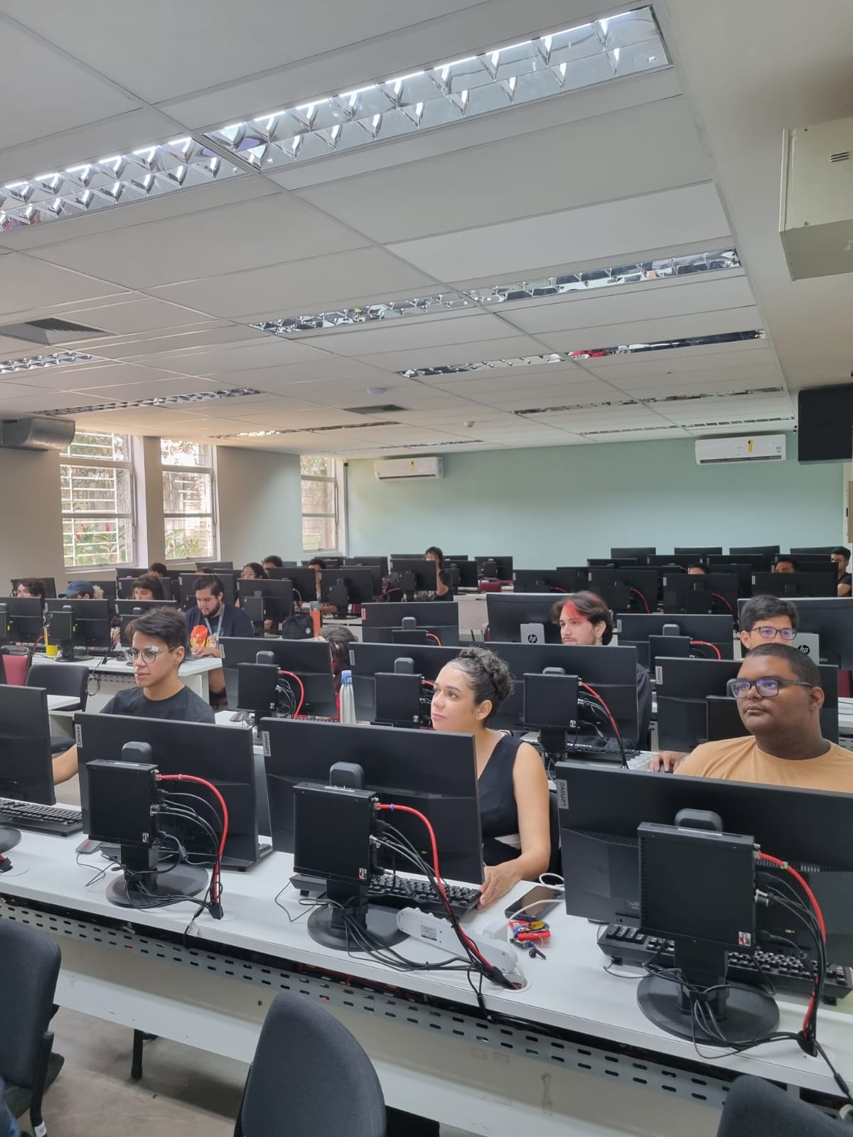 Estudantes em uma sala com computadores assistindo à uma workshop.