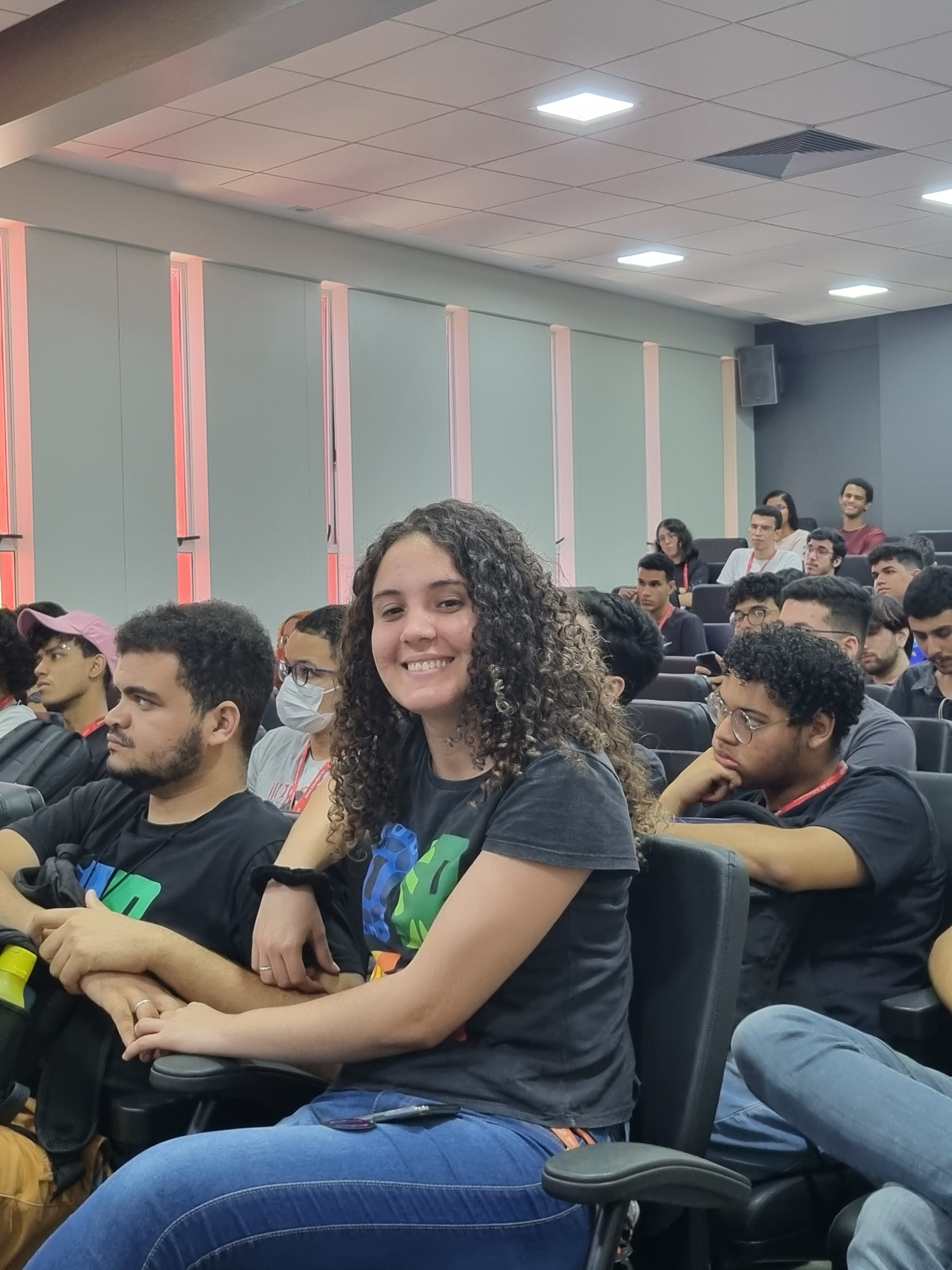 Jovem sorrindo durante uma palestra da semana da computação que aconteceu no anfiteatro do contro de informática da UFPE.