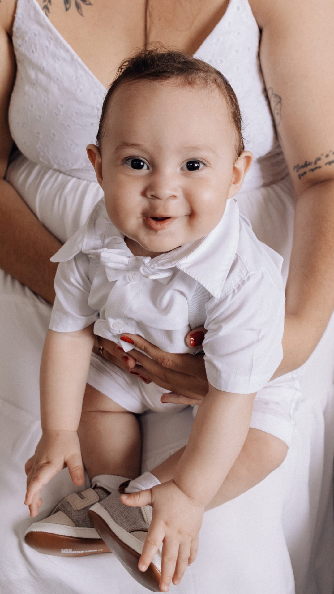 Bebê sorrindo para foto em cerimônia de batizado em Belo Horizonte.