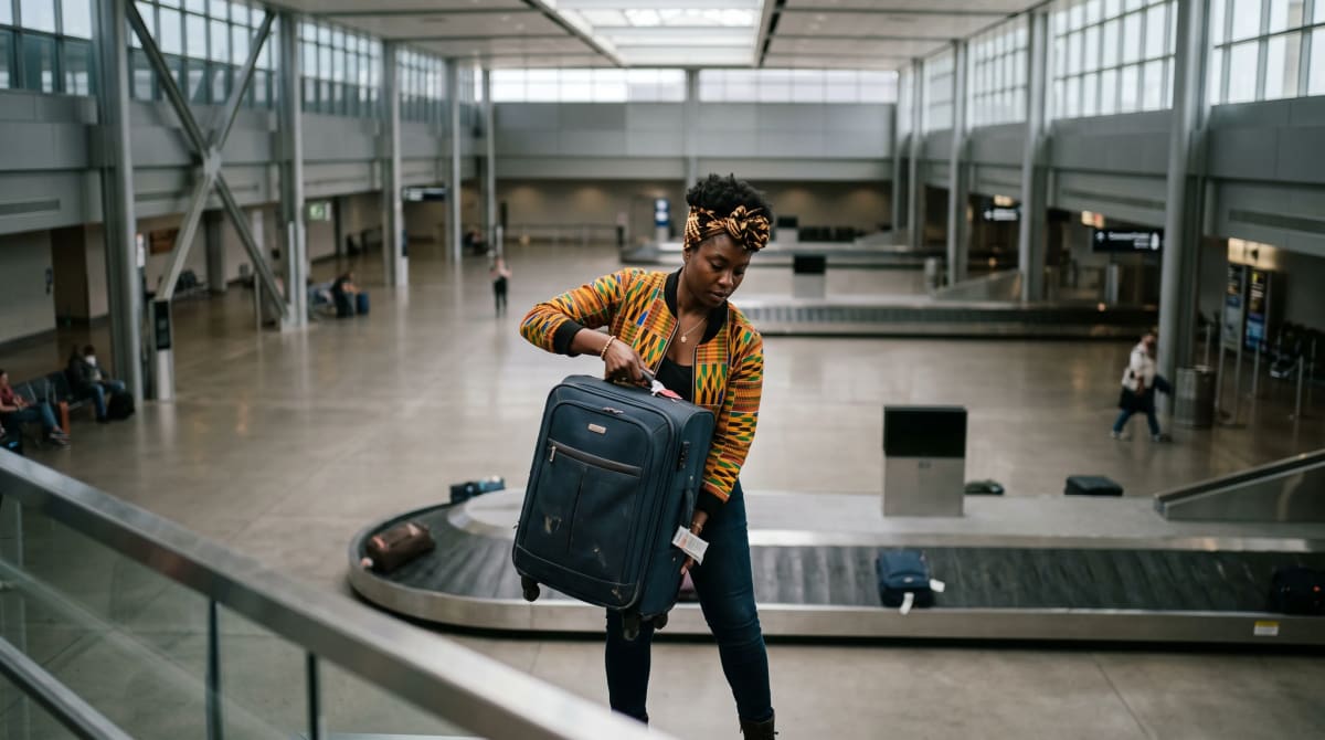 Traveler lifting a suitcase from an empty airport carousel seen from above
