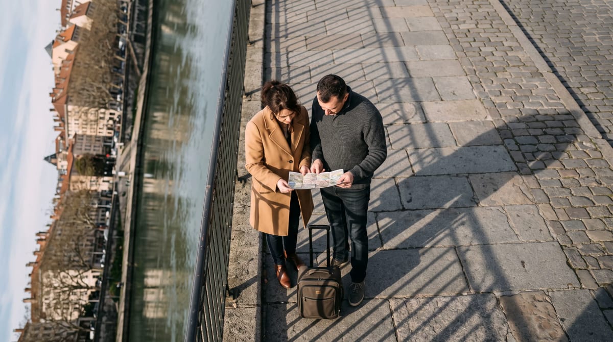 Couple pausing over a paper map on a Lyon riverside promenade at first light
