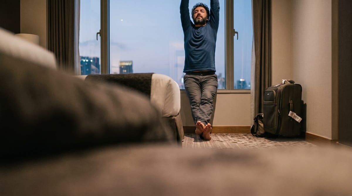 Guest stretching at a hotel window after arriving at dusk