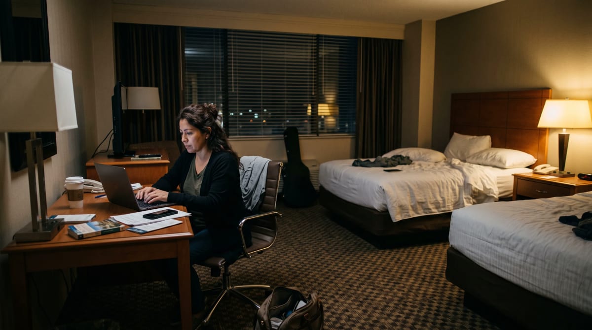 A traveler at a Nashville hotel room desk with a laptop at night