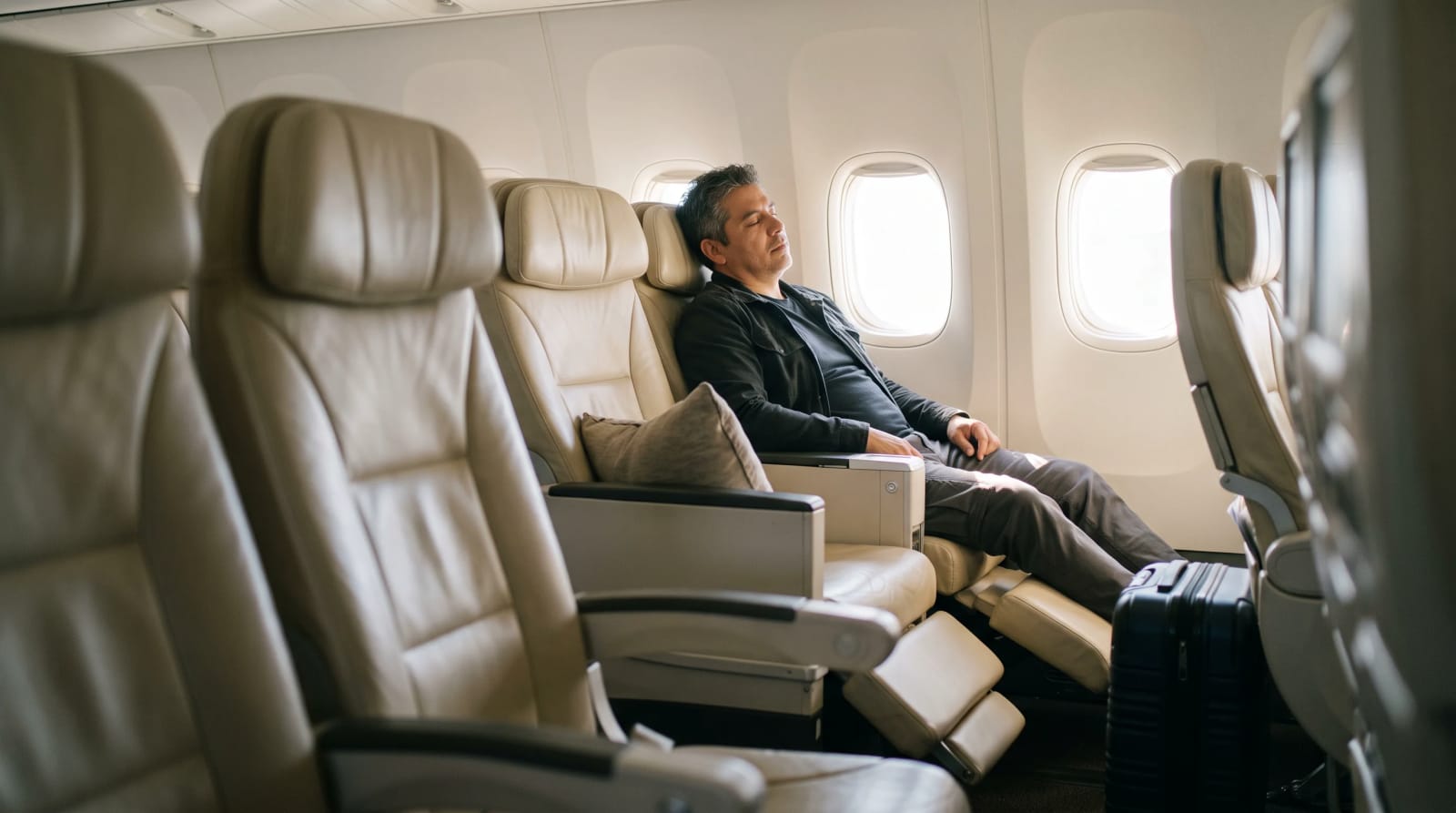 A traveler in cream leather premium economy seat by window
