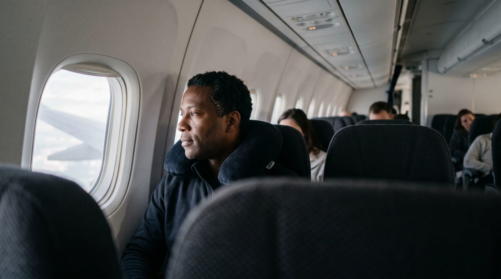 Traveler with pillow by the window in a long-haul cabin