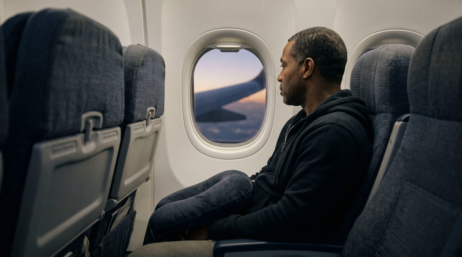 A traveler seated by the window in a long-haul aircraft cabin over New York