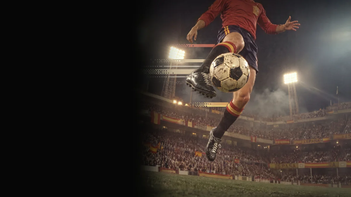 Futbolista con la equipación clásica de la selección española golpeando el balón de volea en un estadio lleno