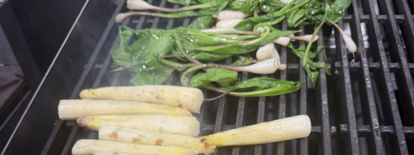 White asparagus and spring onions charring on a kitchen grill