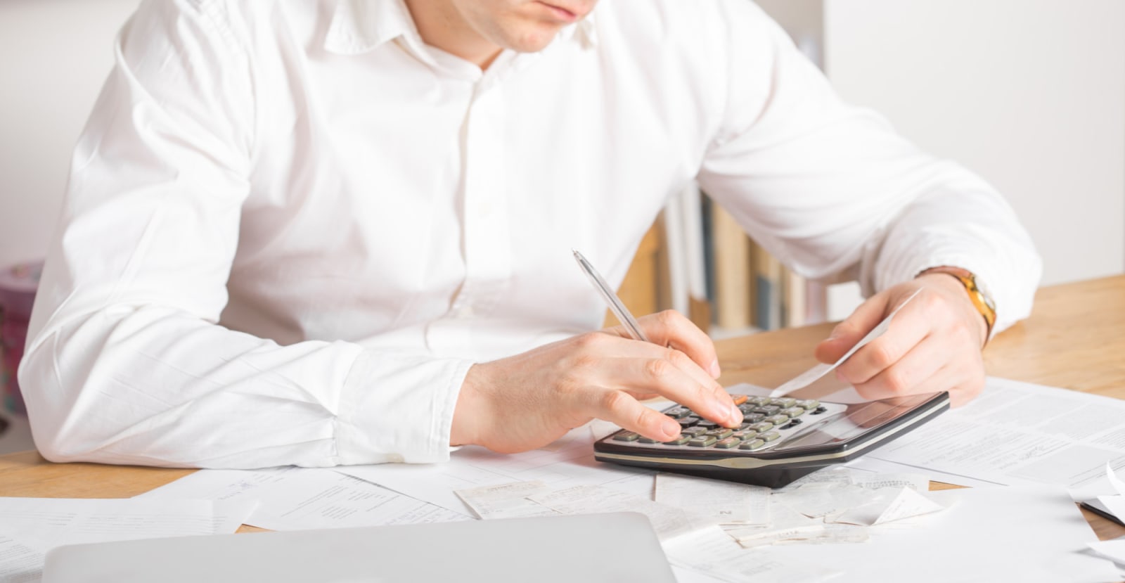 Small business owner reviewing costs with a calculator and laptop / Dueño de negocio revisando costos con calculadora y laptop