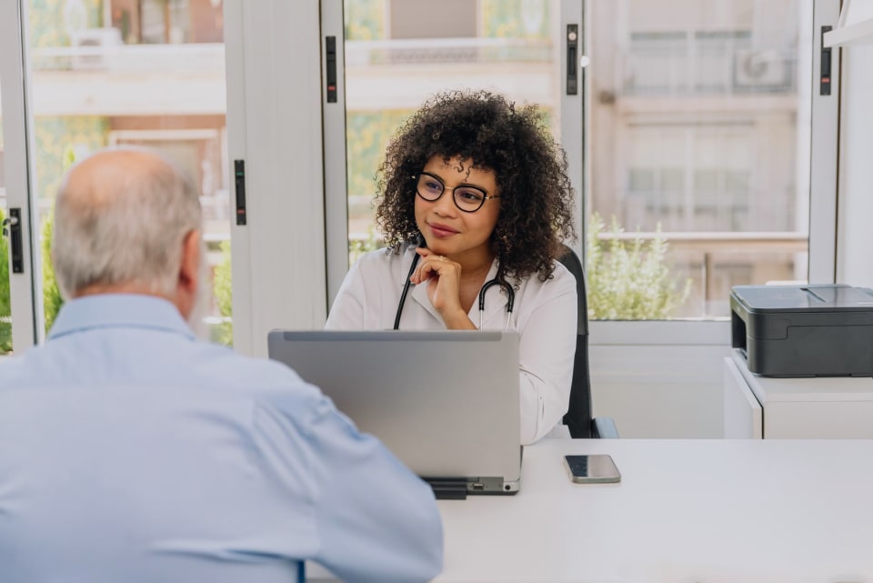 Hispanic doctor sitting across from a patient in the consulting room