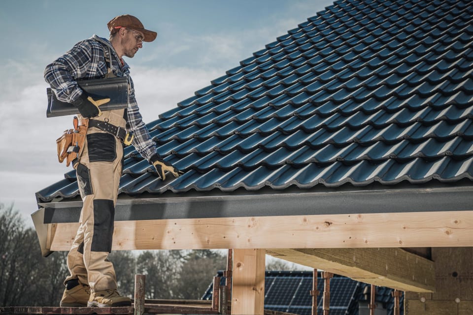 Roofer laying shingles on a house roof