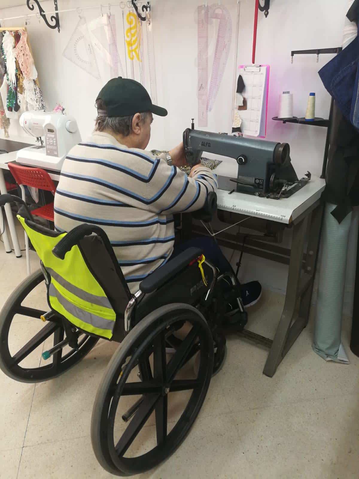 SEWING MACHINES FOR INCLUSIVE PRODUCTION. Image of paco sewing with the adaptation and using his wheelchair.
