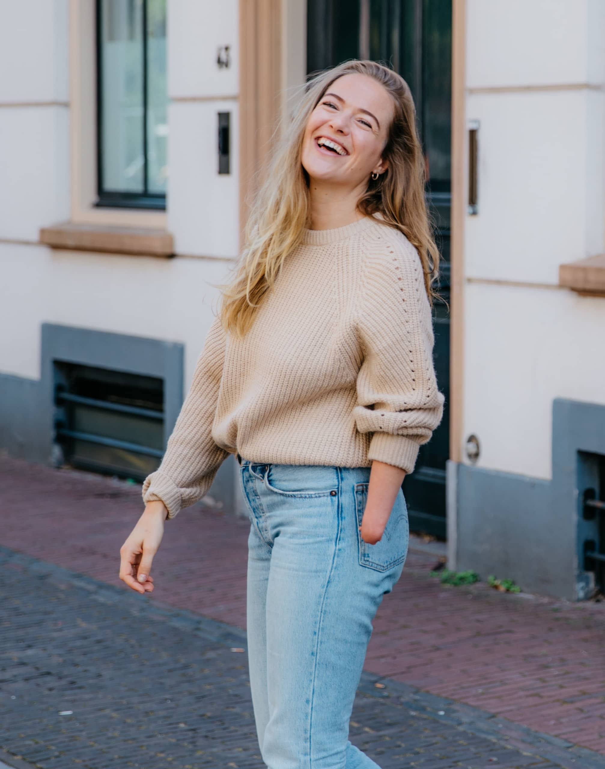 Inclusive fashion training, image of a girl smiling and standing in the street with an amputee arm.