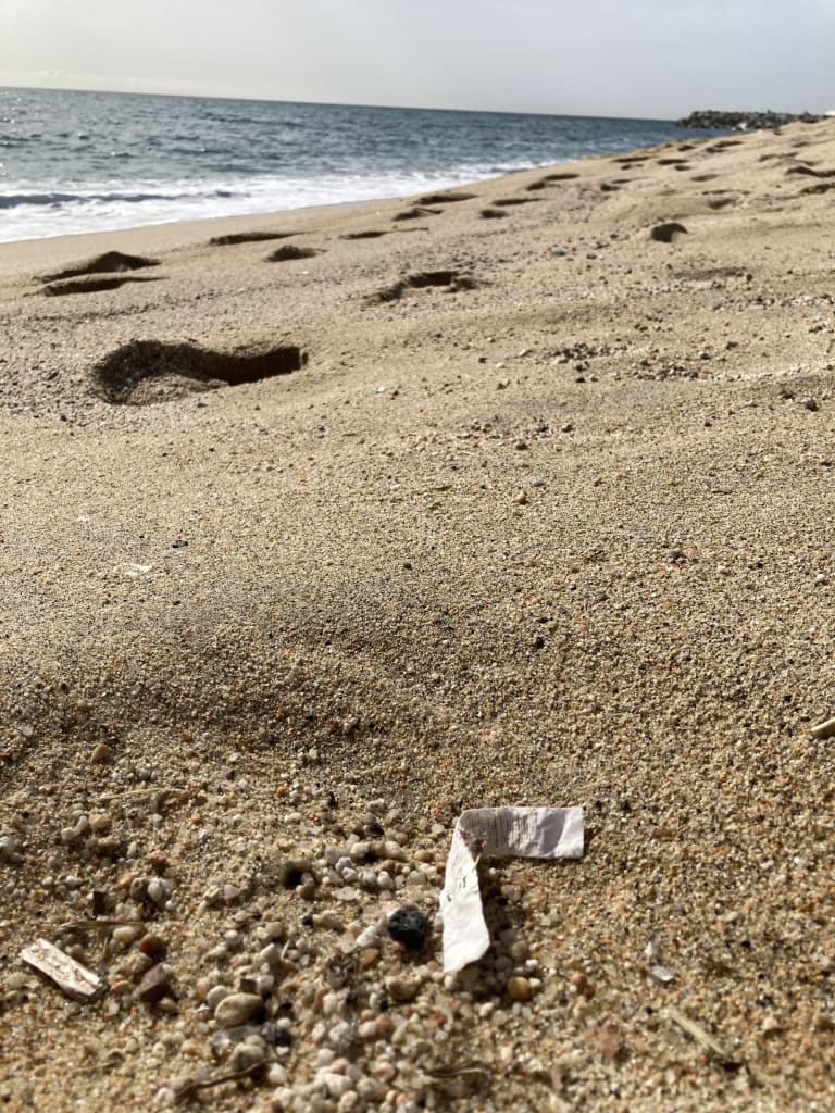 Imagen de una etiqueta de composición desechada en la arena de la playa.