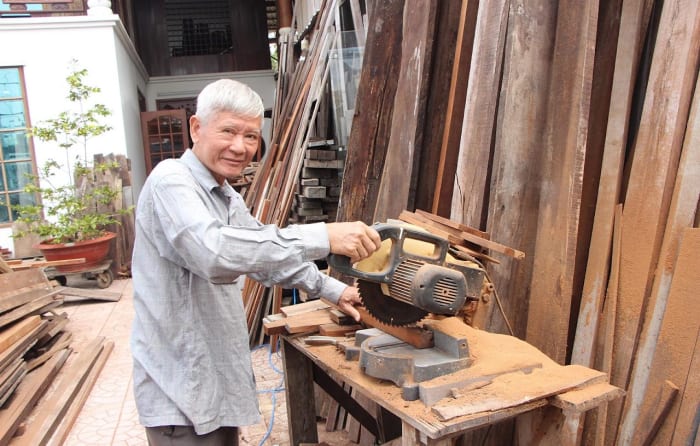 Ông Trần Minh Đoàn bên sản phẩm gỗ trong xưởng