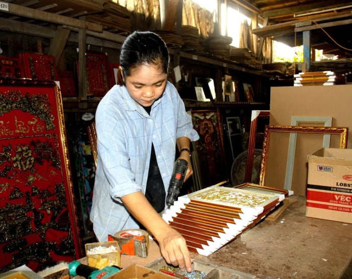 Nghệ nhân nữ bên những tấm tranh kiếng xếp thành hàng