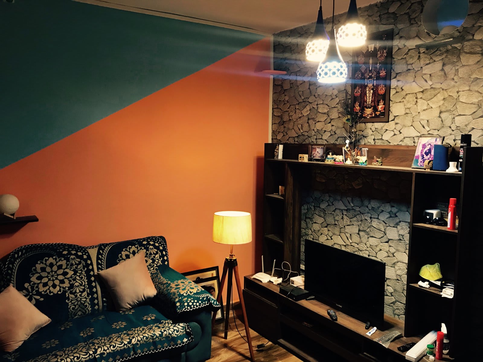 Finished living room with orange and teal wall, TV unit and pendant lights