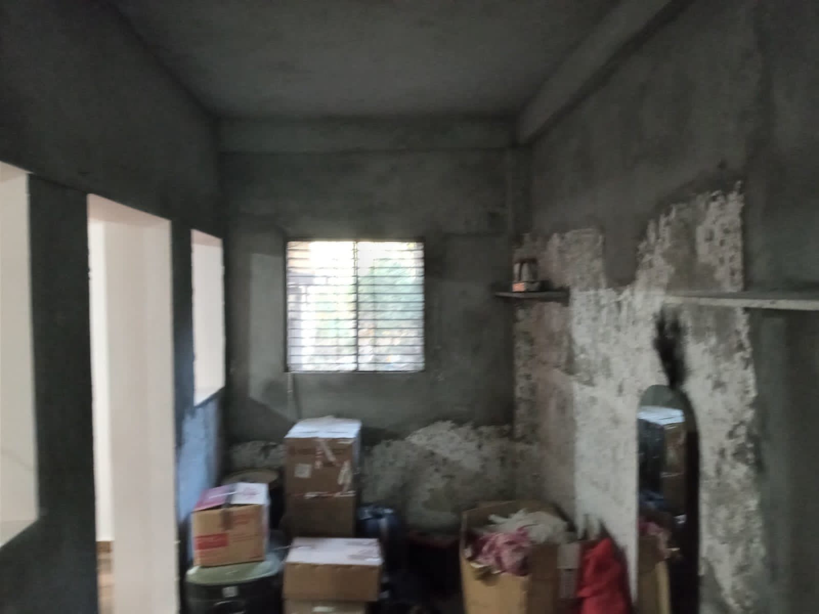 Unfinished room with patched plaster walls and stacked cardboard boxes