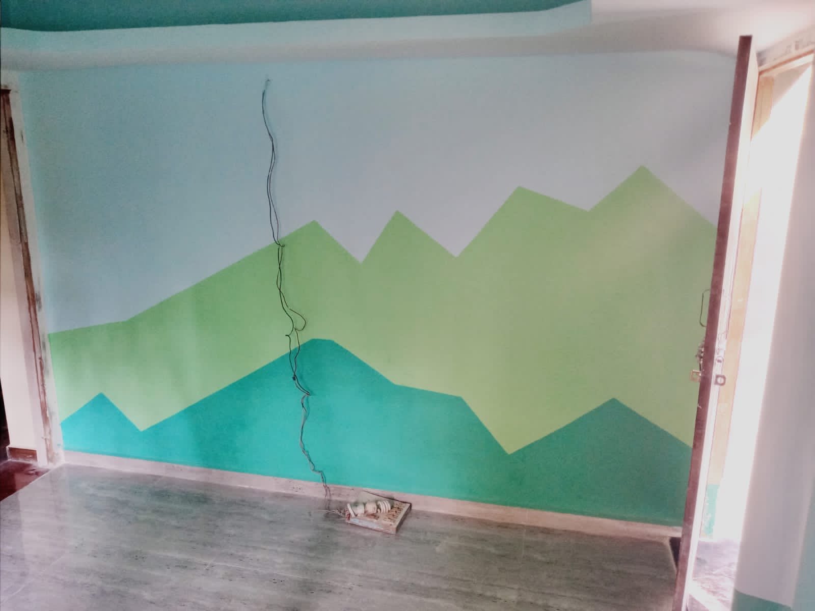Wall painted with layered green mountain shapes
