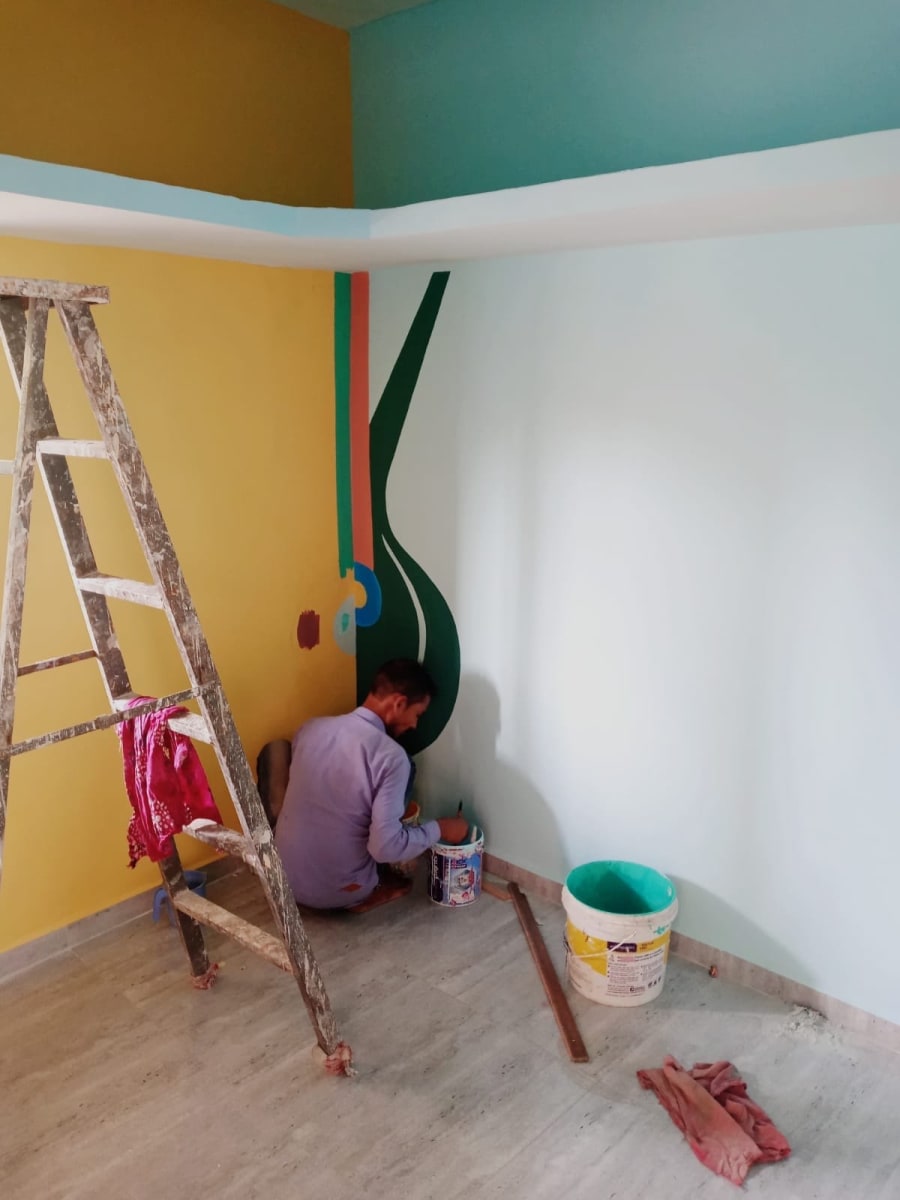 Painter on the floor working on a mural of a stylised string instrument