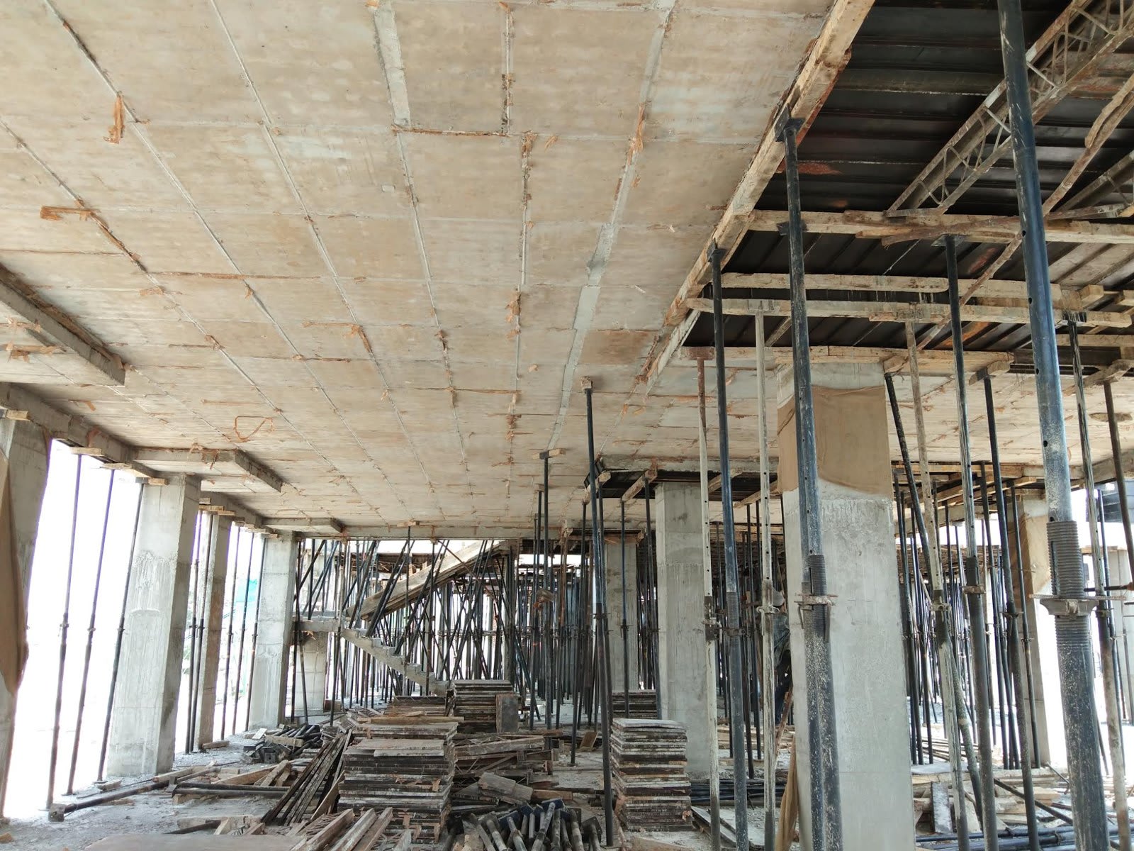Underside of a freshly cast concrete slab held up by steel props and timber formwork