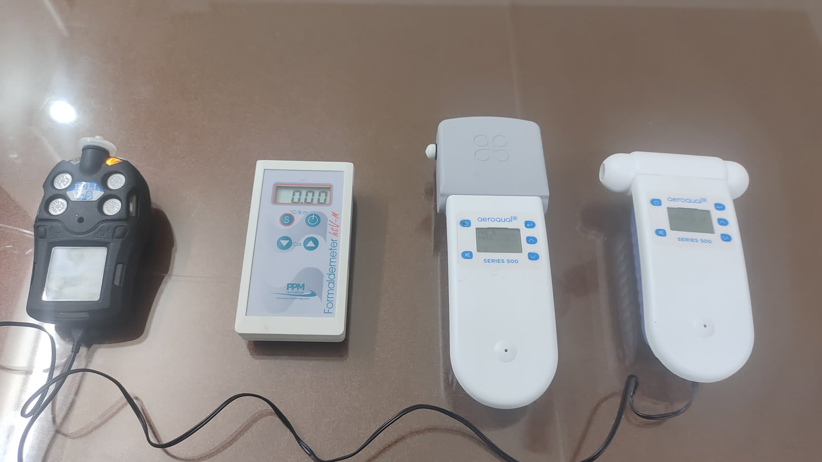 Four handheld indoor air quality instruments laid out on a table: a multi-gas detector, a formaldehyde meter and two gas sensor monitors