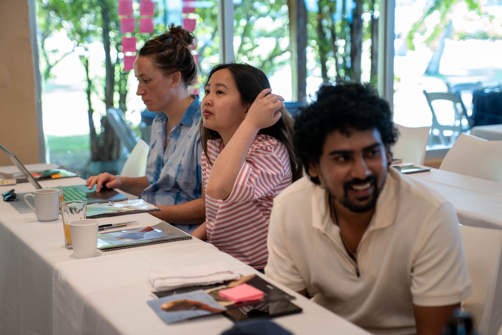 Sagar smiling at a conference table alongside colleagues with notebooks and sticky notes