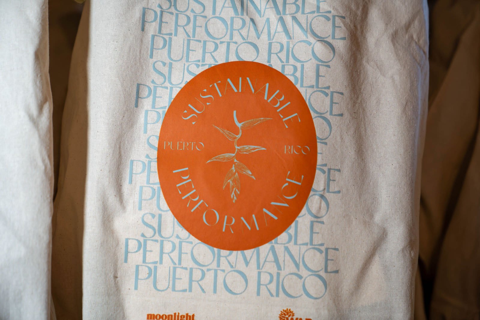 Canvas tote bag printed with "Sustainable Performance Puerto Rico" around an orange seal